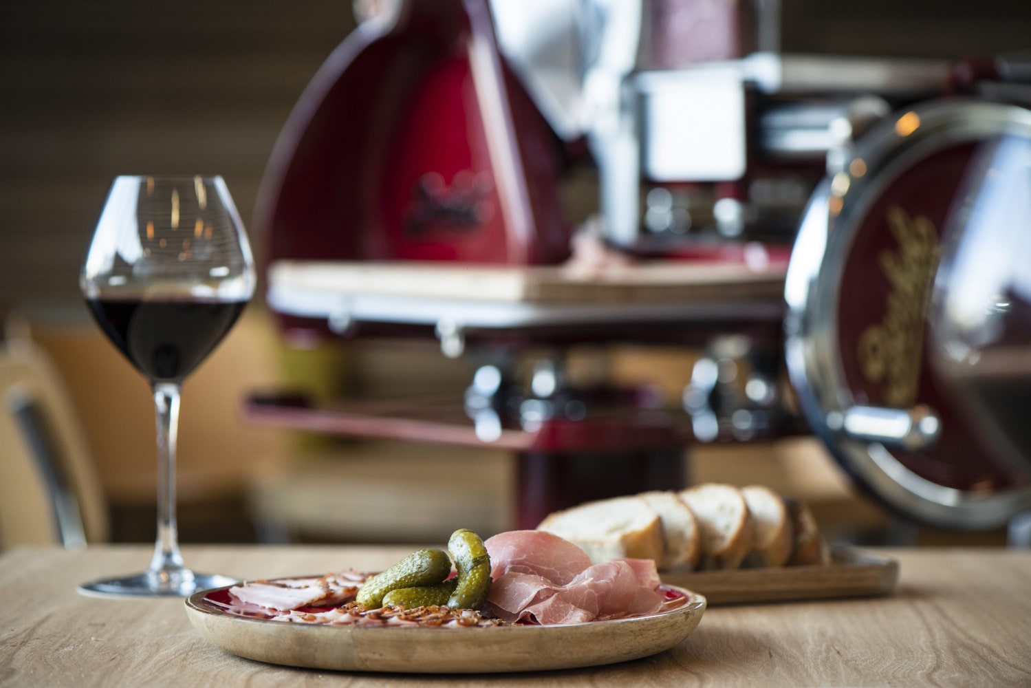 Plan rapproché d'une table du Café-bar Le point Commun sur laquel il y a un plat de viandes sechées ainsi que du pain  et un verre de vin rouge.